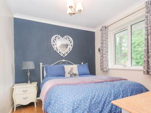 a bedroom with a bed with a heart mirror on the wall at No 1 The Heathers in Saint Cleer
