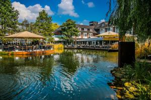 een rivier met tafels en parasols en een restaurant bij Wellings Parkhotel in Kamp-Lintfort
