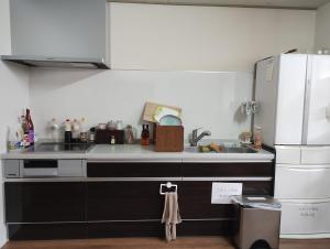 a kitchen with a sink and a refrigerator at Backpackers Kur Guesthouse Asahirou 旅人湯治客舎朝日楼 in Kaga