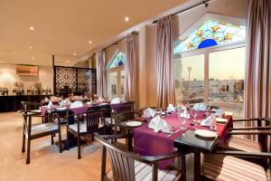 ein Restaurant mit lila Tischen und Stühlen und einem Buntglasfenster in der Unterkunft Al Wadi Hotel in Suhar