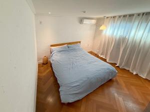 a bed in a room with white walls and wooden floors at Aloha Green Gamcheon in Busan