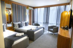 a hotel room with two beds and a chair at Park Hotel Plovdiv in Plovdiv +113 photos