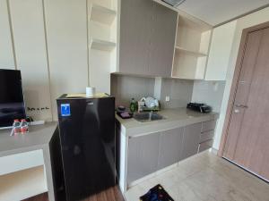 a small kitchen with a black refrigerator and a sink at Apartemen Puri Orchard Lani's Transit Tower CH in Jakarta