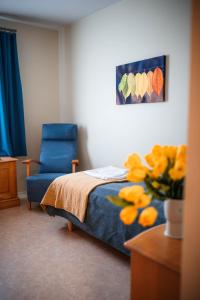 a bedroom with a bed and a chair and a vase of yellow flowers at Kitinrivi B&B in Kannus