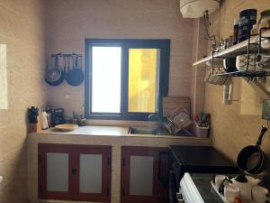 Una pequeña cocina con fregadero y ventana. en Cozy Corner, en Ouakam