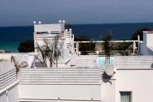 a white building with a swimming pool and the ocean at Playa del Mar - Adults Only in Monopoli