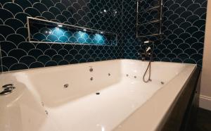a bath tub in a bathroom with a blue tiled wall at St Hildas Complex in Hinderwell