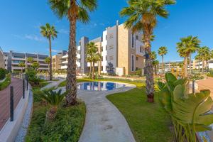 a resort with a swimming pool and palm trees at Playa Flamenca in Orihuela Costa
