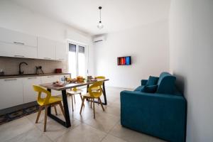 a kitchen and dining room with a table and a blue couch at Donnalucata - 2min dal Mare e AC in Donnalucata