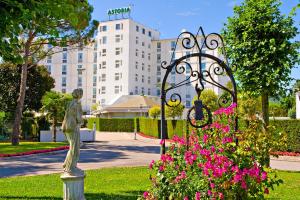 une statue et des fleurs devant un bâtiment dans l'établissement Hotel Abano Astoria, à Abano Terme