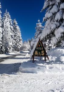 ein Schild im Schnee neben einigen Bäumen in der Unterkunft Vile M&S in Kopaonik