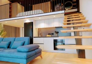 a living room with a blue couch and a staircase at Tirana Sunset Retreat Stylish Loft by the Lake Park in Sauk