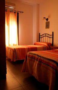a bedroom with two beds and a window at El Aceitón in Cortegana