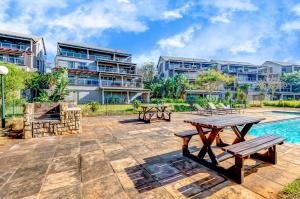 a patio with picnic tables and buildings in the background at 17 Tamboti, Simbithi Eco Estate in Ballito