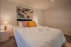 a bedroom with a large white bed with pillows on it at CBD Edge - 2BR Home with Balcony Sleeps 4 in Christchurch