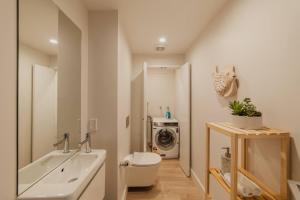 a bathroom with a sink and a washing machine at CBD Edge - 2BR Home with Balcony Sleeps 4 in Christchurch +29 photos