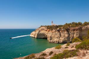 a boat in the ocean on a cliff at Kimpton Atlantico Algarve by IHG in Albufeira