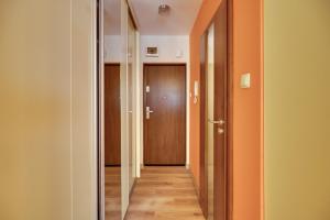 un couloir vide avec une porte et un couloir revêtu de parquet dans l'établissement Orange by OneApartments, à Gdańsk