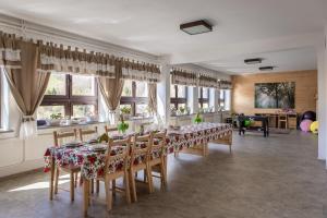 a dining room with tables and chairs and windows at Honey Inn - Domek na 12 osób in Kamianna