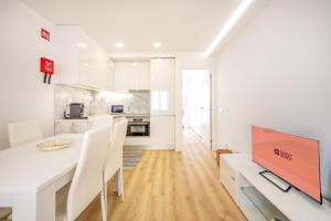 a white kitchen with a dining table and a tv at GuestReady - Sunny Sesimbra Escape in Sesimbra +19 photos