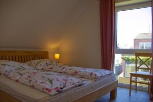 Una cama en un dormitorio con una ventana grande. en Inselblume 27 - Modernes Ferienhaus mit Garten in Burg, en Burg auf Fehmarn