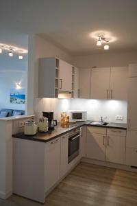 una cucina con mobili bianchi e un piano di lavoro di Inselblume 44 - Ferienwohnung mit Balkon im Zentrum von Burg a Burg auf Fehmarn