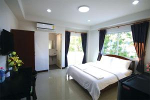 a bedroom with a white bed and a large window at Baan Samrarn in Krabi town