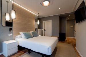 Un dormitorio con una cama blanca y un televisor. en Avenida Lofts, en A Coruña