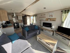 a living room with a couch and a table at The Retreat 10 - Hot tub Mini Lodge, central heating, bed linen, & pet friendly - Meadow Lakes Caravan Hire in Chapel Saint Leonards