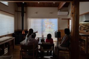 a group of people sitting around a table watching a presentation at Cottage Roots コテージルーツ in Hida