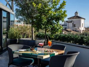 a table and chairs on a rooftop patio with a tree at Sofitel Roma Villa Borghese in Rome
