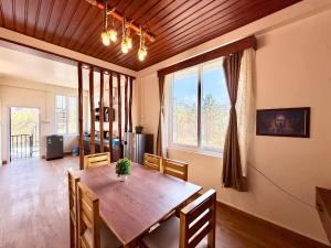 una sala da pranzo con tavolo in legno e ampia finestra di Yepplo Holiday Home - Complimentary Breakfast - 24 hrs Caretaker & Power Backup a Shillong