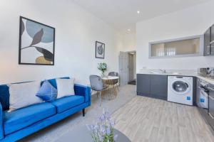 Una sala de estar con un sofá azul y una cocina. en Modern & Cosy 1 Bedroom Budget Apartment in Dudley, en Brierley Hill