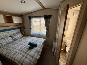 a small bedroom with a bed with a teddy bear on it at The Retreat 10 - Hot tub Mini Lodge, central heating, bed linen, & pet friendly - Meadow Lakes Caravan Hire in Chapel Saint Leonards