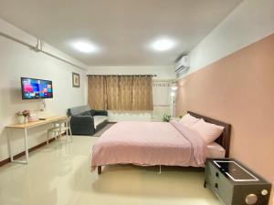 a bedroom with a bed and a desk and a television at La Maison 230 in Ban Khlong Samrong