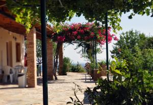 a patio with pink flowers hanging from a pergola at Panorama Apartments updated with infinity pool in Agios Nikolaos