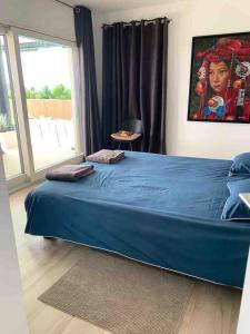 a bedroom with a large blue bed with a window at Appart avec piscine chauffée et plage 5 min in Perroy