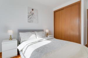 Un dormitorio con una cama blanca y una puerta de madera. en Câmara de Lobos Apartment by Holiday Rental Madeira, en Câmara de Lobos