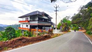 a house on the side of a road with a motorcycle at DevaDheyam Homestay in Munnar
