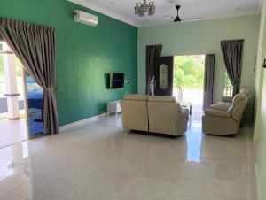 a living room with two couches and a green wall at Nok D'Jelutong Homestay Sik Kedah in Sik