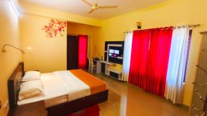 a bedroom with a bed with red curtains and a television at DevaDheyam Homestay in Munnar +30 photos
