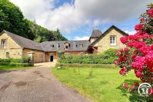 a stone house with a black roof and pink flowers at Domaine de lafayette - sejours bien-etre et detente in Saint-Marcel