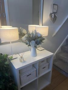 a table with two lamps and a vase with flowers on it at The Glastonbury Townhouse B&B in Glastonbury
