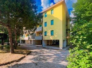 an exterior view of a yellow building with trees at Bright and cozy flat for 6 guests in Bibione Pineda