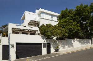 um edifício branco com uma garagem em frente em Bayflowers Guest House na Cidade do Cabo