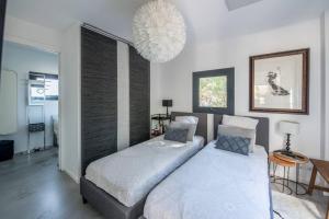 una camera da letto con due letti e un lampadario di Arcachon-Moulleau Belle villa avec piscine et jardin privés a La Teste-de-Buch Altre 10 foto