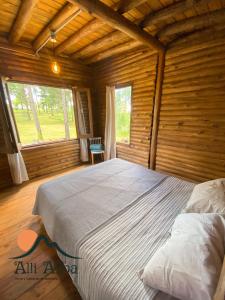 a bedroom with a large bed in a log cabin at Alli Allpa Finca y Cabañas de Montaña in Villa Yacanto +34 photos