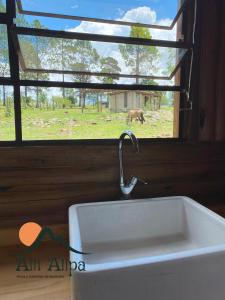 a sink with a faucet in front of a window at Alli Allpa Finca y Cabañas de Montaña in Villa Yacanto