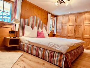 a bedroom with a bed with white sheets and pink pillows at TONIS cozy Boutique Chalet by ALPIN CHARME APARTMENTS in Reith bei Kitzbühel