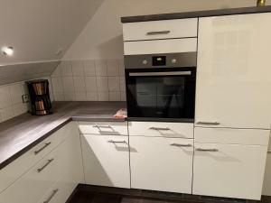 a kitchen with white cabinets and a microwave at Stilvolles Apartment mit Dachterrasse in Garbsen